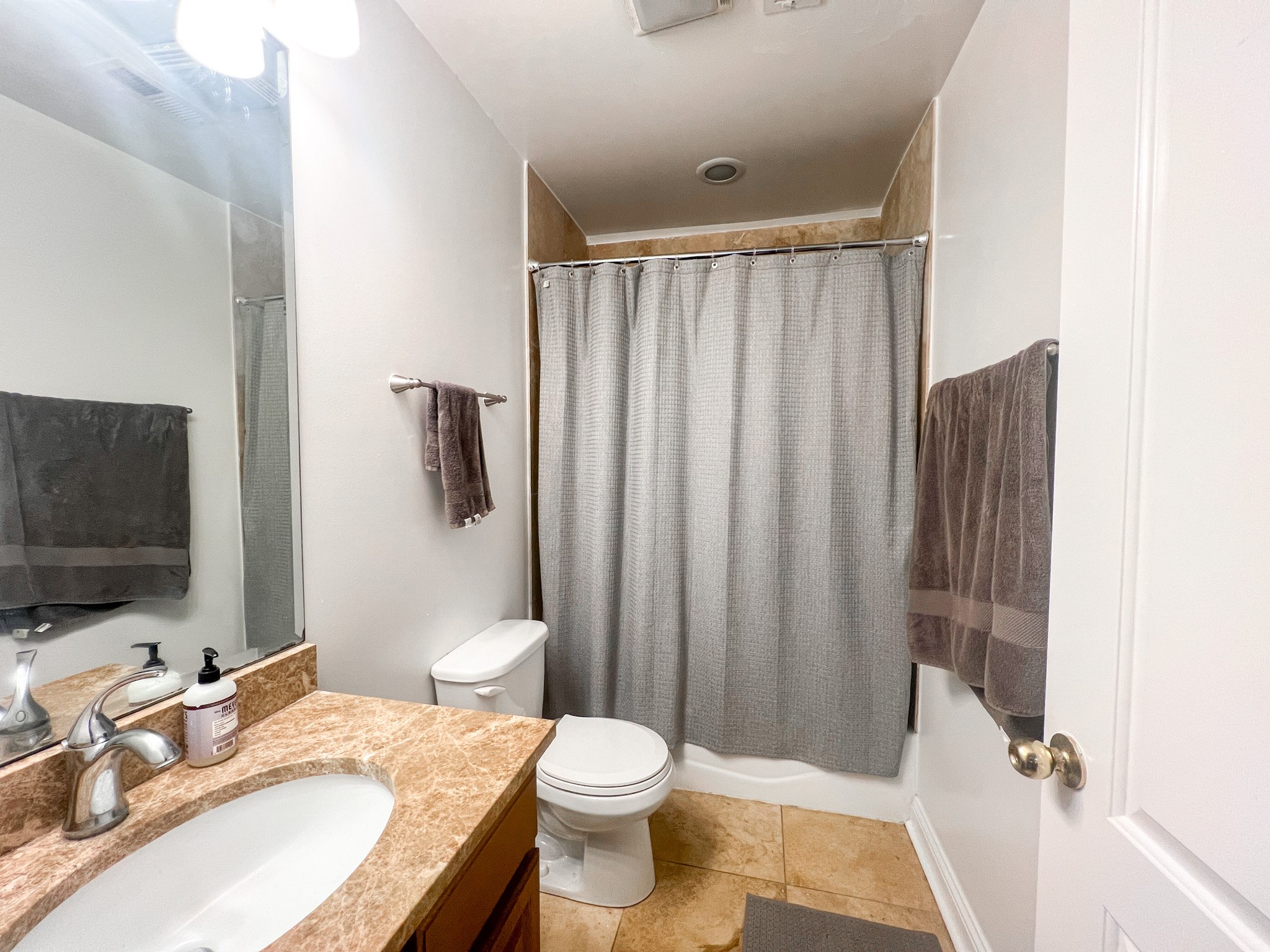 A bathroom with a toilet, sink, and shower curtain.